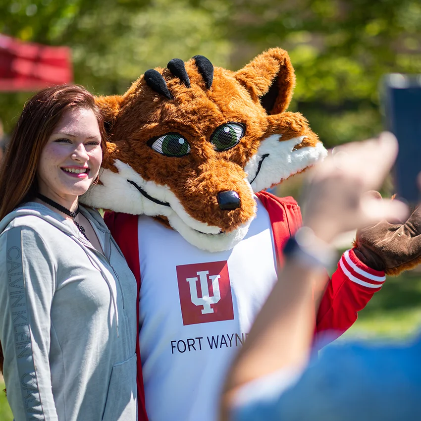 Student posing with Ruby the Red Fox at IU Fort Wayne