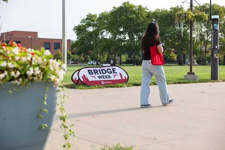 Student walking past a Bridge Week sign