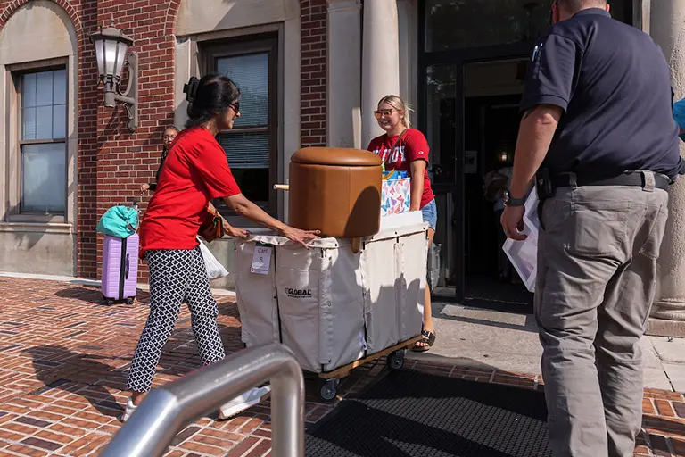 Chancellor Ramchand helping a student move a cart into a residence hall