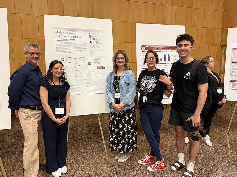 Group of people at student research conference standing in front of posters