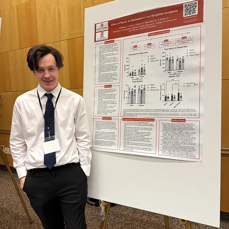 Student standing next to poster about the effects of music on nociception and morphine analgesia