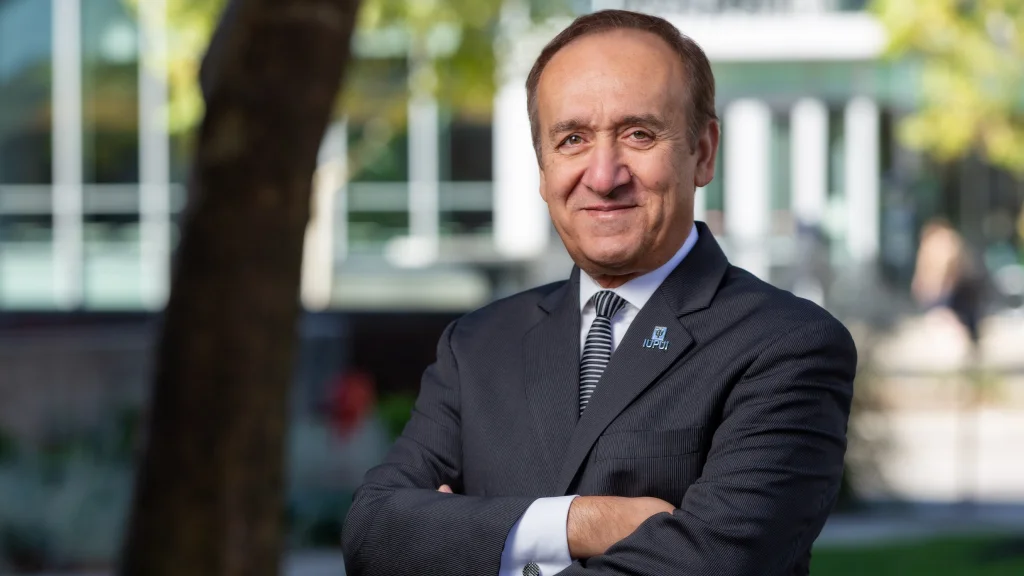 Chancellor Nasser H. Paydar stands in a suit, arms crossed, posing for a portrait.