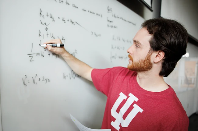 A student writing equations on a whiteboard