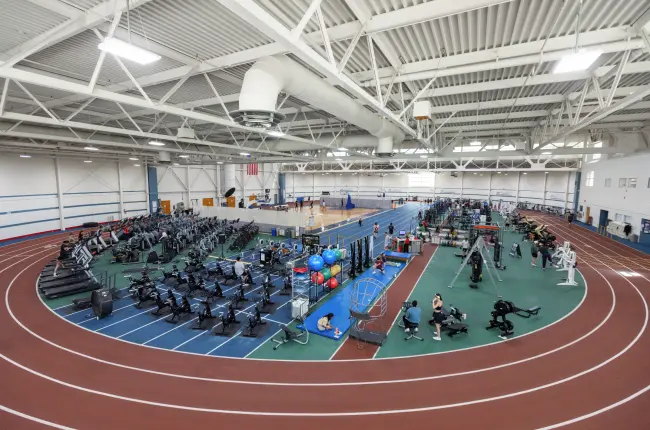 Indoor fitness center with cardio and strength equipment, surrounded by a running track.