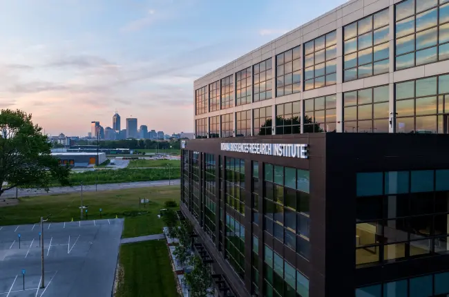 Indiana Biosciences Research Institute building with modern glass exterior and a backdrop of the Indianapolis city skyline.