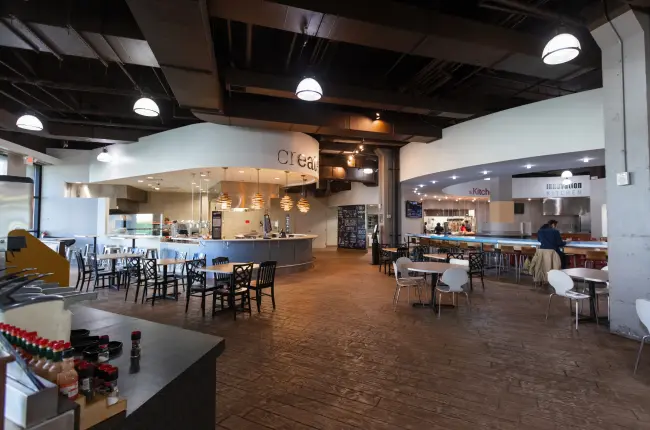 Spacious dining hall with modern decor, multiple food stations, and various seating options.