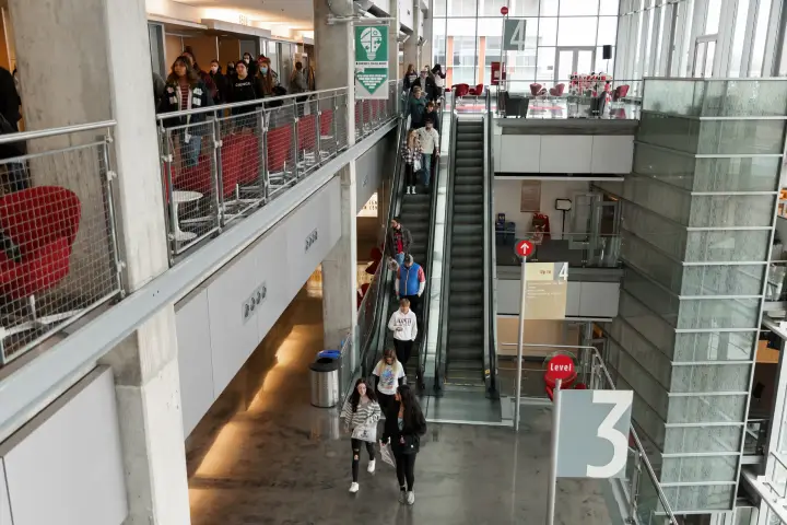 Students riding the escalator inside the Campus Center atrium