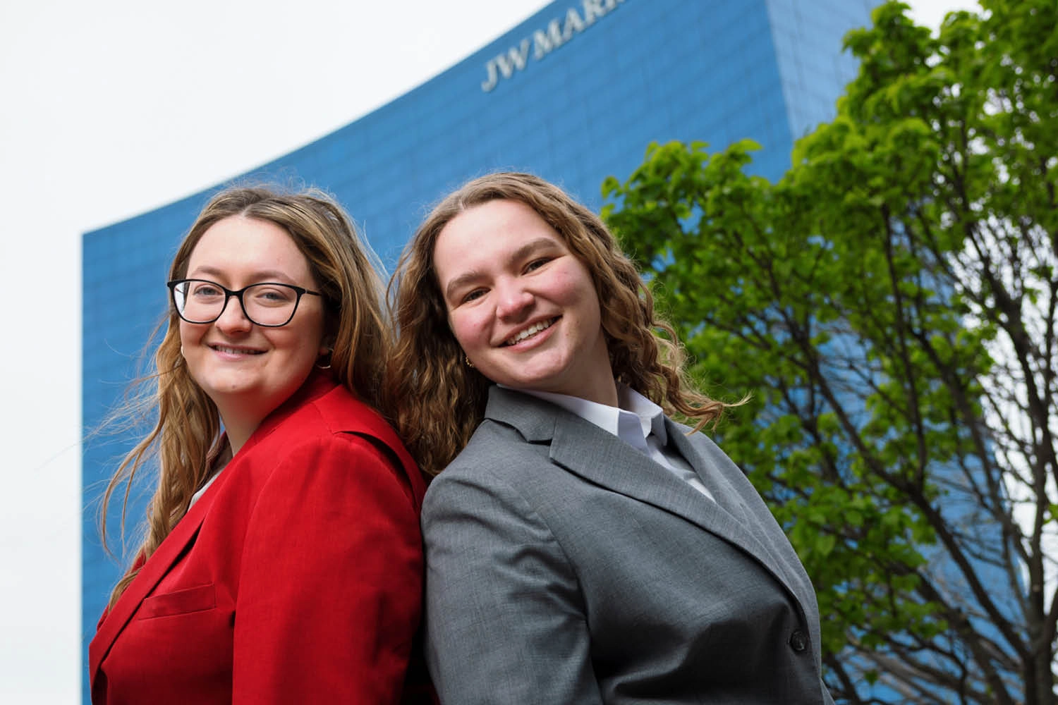 Two women in sports coats stand back to back in front of the J W Marriott hotel in downtown Indianapolis, Indiana.