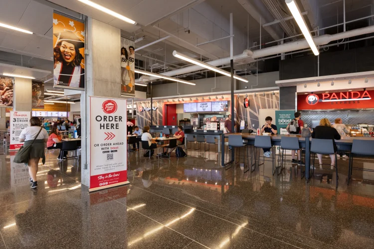 A crowded, modern food court with a variety of vendors and ordering options.