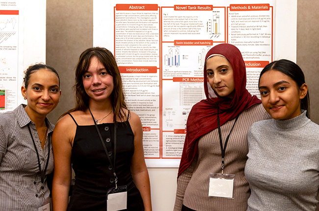 Four students standing in front of a research poster