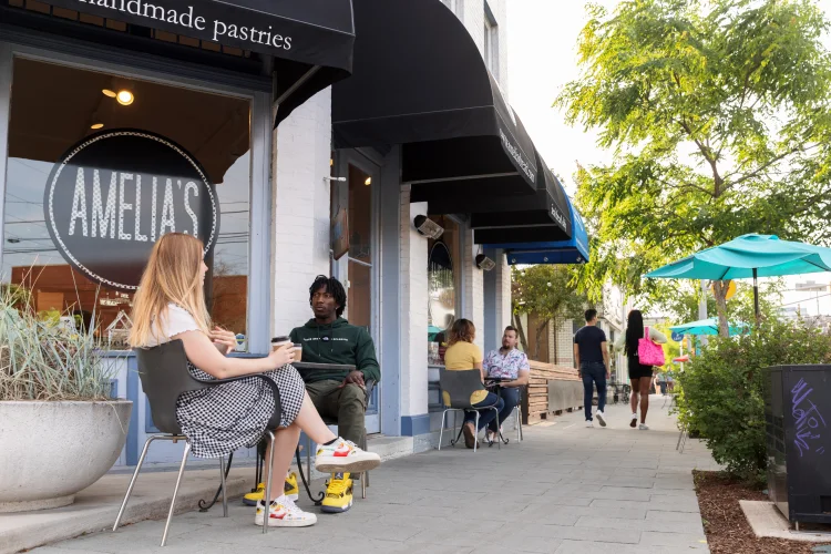 People sit at outdoor tables along outside a bakery along the Cultural Trail.