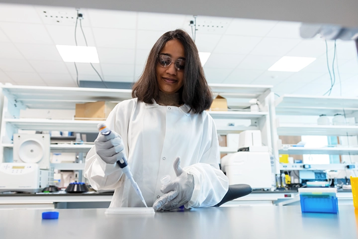 A student uses a pipette in a laboratory.