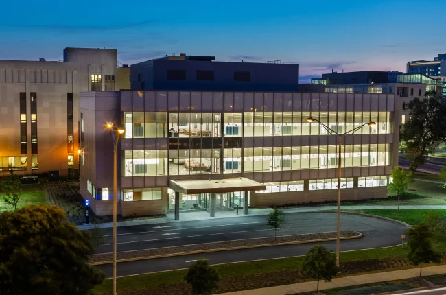 Windows lit up at the School of Dentistry at dusk.
