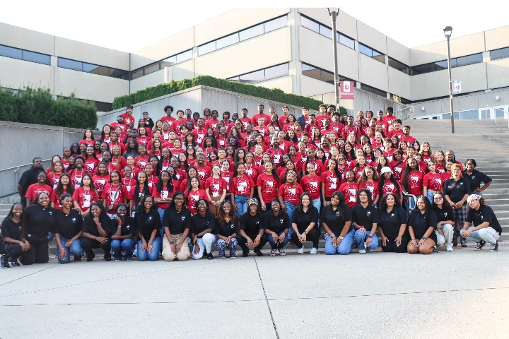 People in red and black shirts gather on the steps near University Library.
