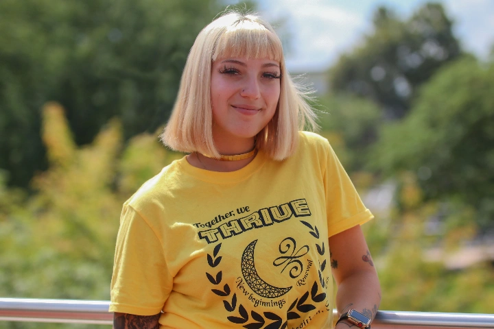 A THRIVE student poses in front of some trees.