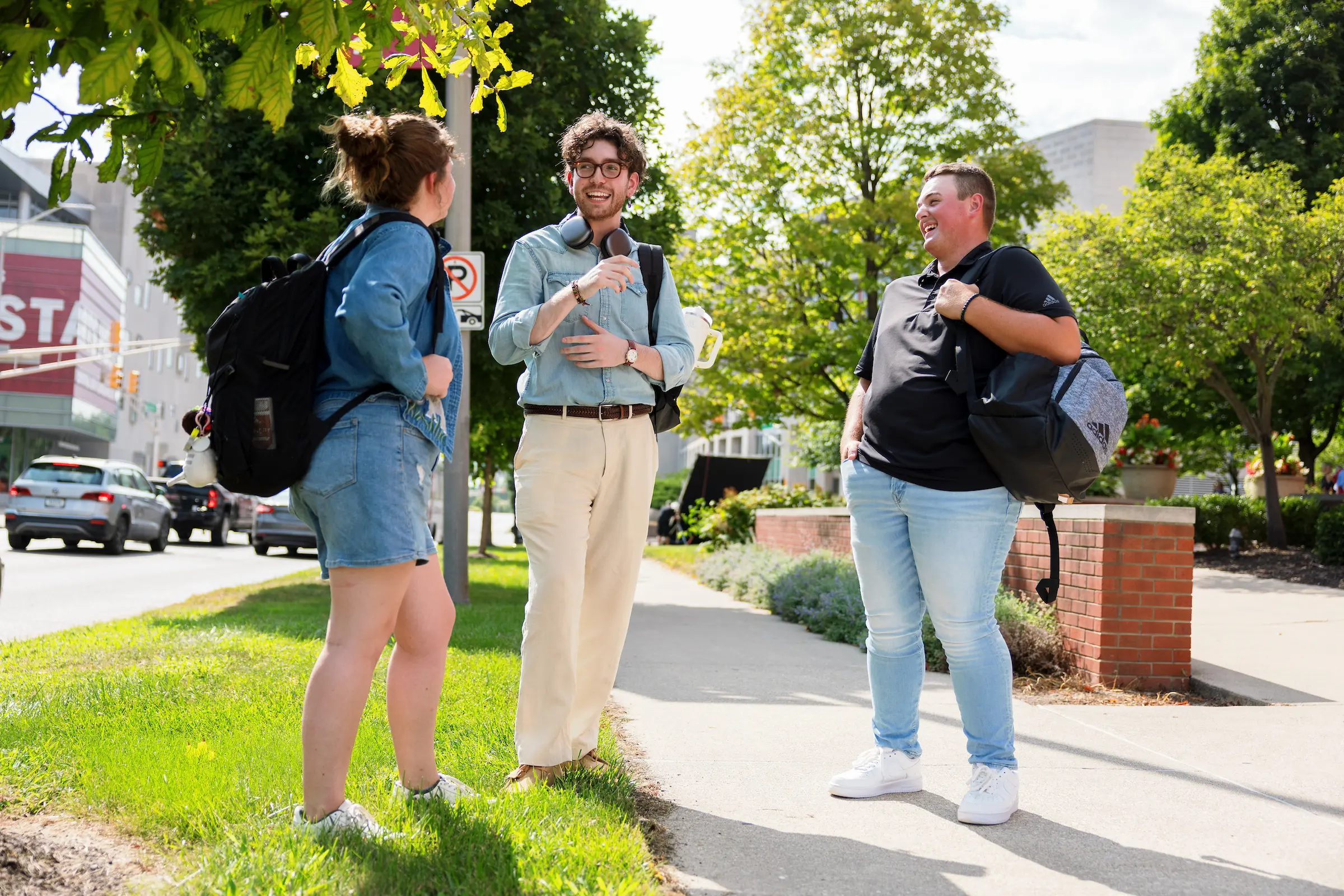 Three people smile and laugh in an outdoor green space on the IU Indianapolis campus.