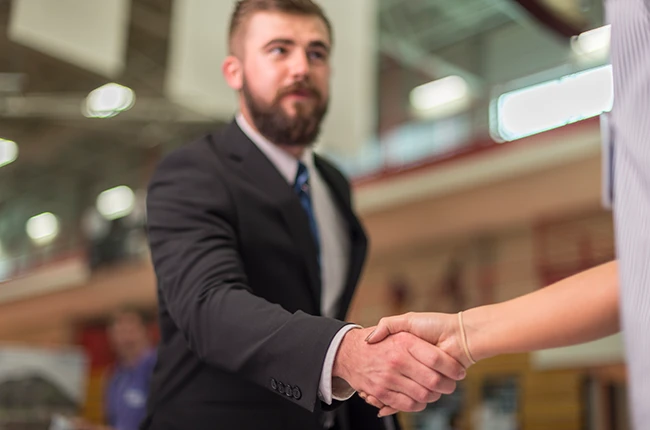 Person in a suit shaking hands with with another person