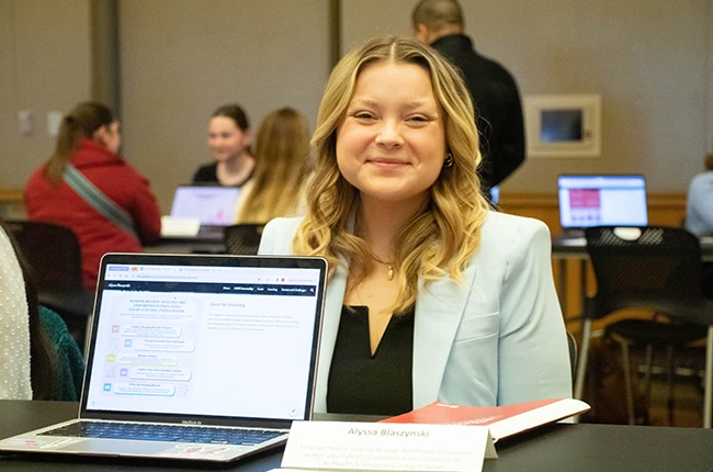 Student smiling with a presentation about their internship experience