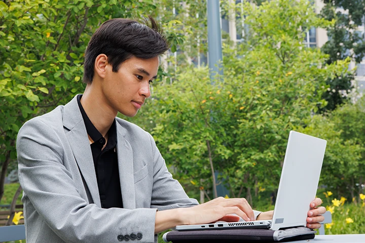 A person sitting outside looking at a laptop