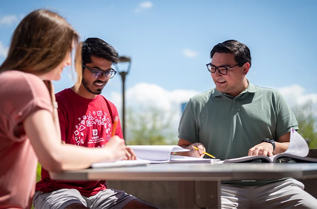 Three students doing homework together outside