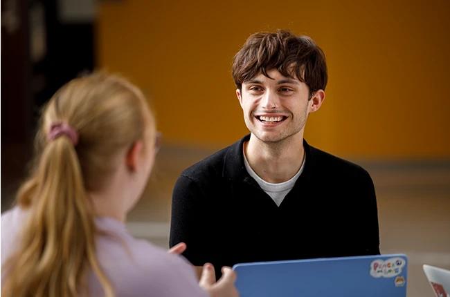 Two people talking in front of a laptop