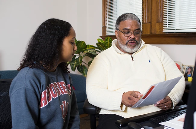Two people talking and looking at papers together