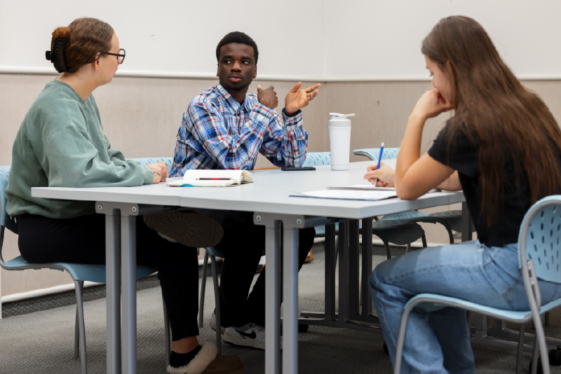 three students collaborating in a classroom setting.